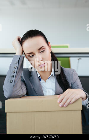 Ritratto di una donna con una scatola di cartone sul suo giro che è stato reso ridondante Foto Stock