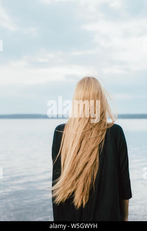 Capelli lunghi donna che guarda al lago sul giorno di estate Foto Stock