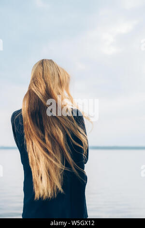 Ritratto di donna con torna alla fotocamera in piedi e guardare oltre il lago Foto Stock