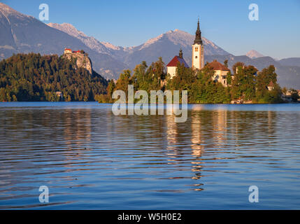 La Slovenia, Alta Carniola, Bled Bled Island e la chiesa dell'Annunciazione dalla riva del lago con il castello di Bled in background. Foto Stock