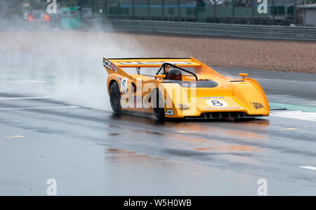 Dean avanti, alla guida della sua 1972, Orange, McLaren M8F, sotto la pioggia, durante il tuono HSCC gara sportiva, al 2019 Silverstone Classic Foto Stock