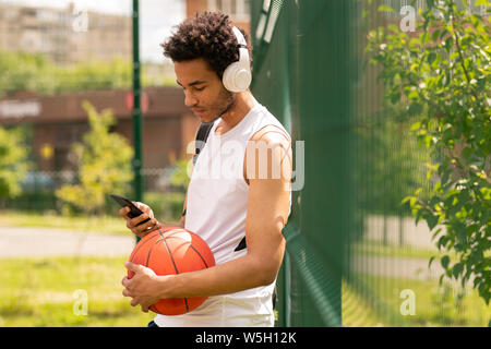 Giovane atleta bello in sportswear ascoltando la musica nelle cuffie Foto Stock