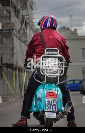 Cheltenham GLOUCESTERSHIRE REGNO UNITO IL 28 LUGLIO 2019 uno scooter pilota sul suo Lambretta scooter indossando un Union Jack casco design Foto Stock