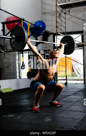 Uomo muscolare con barbell in un allenamento Foto Stock