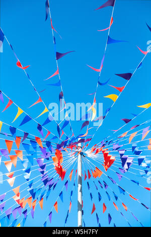 Colorato bunting attaccato ad un palo visto contro un luminoso cielo blu. Foto Stock