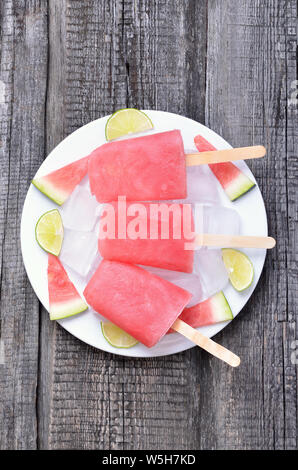 Popsicles da anguria congelata sul tavolo di legno, vista dall'alto. Foto Stock