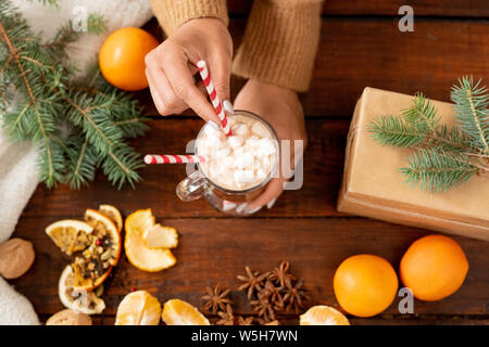 Panoramica di mani umane tenendo un bicchiere di latte con marshmallow Foto Stock