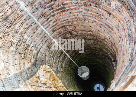 Secchio di plastica nella vecchia antiche acque sotterranee bene. vintage pozzi artesiani. Foto Stock