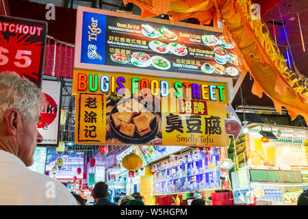 Maschio caucasico turistico con cibo di Bugis street market firmare al famoso mercato di Bugis in Singapore Foto Stock