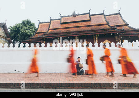 I monaci buddisti durante il laotiano tradizionale elemosina sacra cerimonia in Luang Prabang city, Laos. Una lunga esposizione, oggetto sfocato Foto Stock