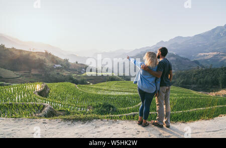 Giovane coppia caucasica guarda alle terrazze di riso di Sapa al tramonto in Lao Cai regione del Vietnam Foto Stock