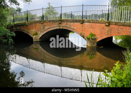 Mattone rosso ponte arcuato con ringhiera di metallo sopra il fiume Avon in alto a Woodford Salisbury Inghilterra Foto Stock