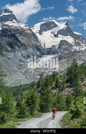 Attiva donna senior, cavalcando la sua mountainbike elettrico sotto il famoso Gornergrat in Zermatt, in background e Rimpfischhorn Strahlhorn,Wallis,sw Foto Stock