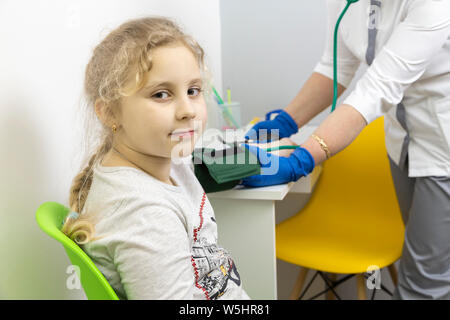 Il medico misura la pressione del sangue del bambino con un tonometro. misure preventive Foto Stock
