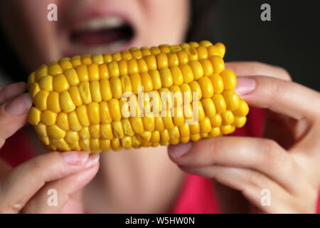 Donna mangia bollito di mais dolce, cob in mani femminili close up Foto Stock