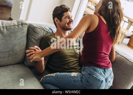 Spensierato giovane godendo di essere insieme a casa. L uomo e la donna seduta su un divano con un grande tempo insieme. Foto Stock