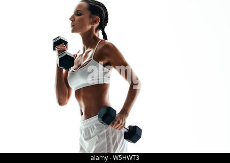 Montare la donna nel sollevamento pesi a manubrio su sfondo bianco con copia spazio. Femmina sportivo in abbigliamento sportivo facendo bicipite allenamento con i pesi. Foto Stock