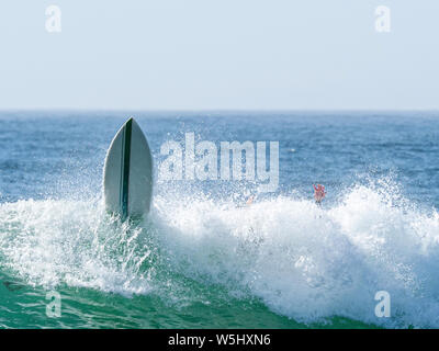 Surfer cadere la sua scheda in una delle onde della costa di Borderia nell' Algarve in Portogallo Foto Stock