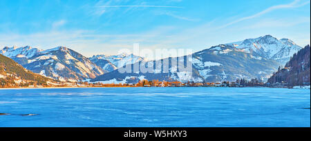 A piedi lungo l'Esplanade terrapieno di frozen Zeller (lago) con una vista sul suo luminoso blu superficie, Alpi innevate e gli alberi di Elisabeth Park, Zell un Foto Stock