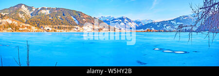 Godetevi l'inverno nelle Alpi e osservare il luminoso blu superficie del lago Zeller See, ricoperta di ghiaccio e neve crosta, Zell am See, Austria Foto Stock