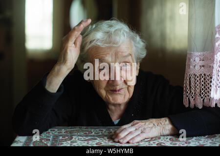 Ritratto di un vecchio grigio-dai capelli donna nella sua casa. Close-up. Foto Stock