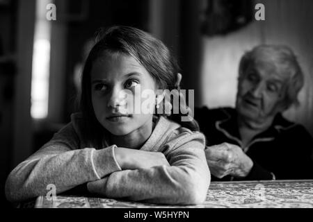 Una vecchia donna trecce una bambina - nipote capelli lunghi. Foto in bianco e nero. Foto Stock