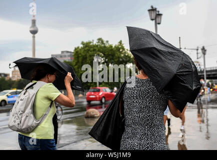 29 luglio 2019, Berlin: due donne cercano di proteggersi dalla pioggia con ombrelloni. Foto: Britta Pedersen/dpa-Zentralbild/dpa Foto Stock