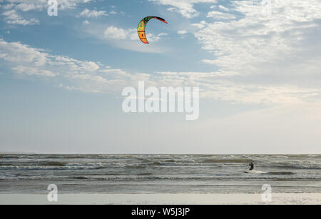 Irlanda kitesurf e kite surfer che scivolano nell'Oceano Atlantico in calda luce del tramonto a Liscanor Bay nella contea di Lahinch Clare Irlanda Foto Stock