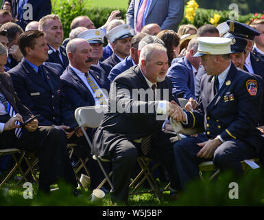 Luglio 29, 2019, Washington, Distretto di Columbia, Stati Uniti d'America: Da sinistra: Gerard Fitzgerald, uniformata dei vigili del fuoco il presidente dell Associazione e Jake Lemonda, Presidente del fuoco in uniforme degli ufficiali di associazione, guarda su come Philip Alvarez scuote le mani con fuoco ex capo della Midtown Manhattan firehouse Chief John Joyce prima del Presidente degli Stati Uniti Trump firma H.R. 1327, un atto per autorizzare permanentemente il 11 settembre vittima del fondo di compensazione, nel Giardino delle Rose della Casa Bianca di Washington, DC il lunedì 29 luglio, 2019. Credito: Ron Sachs/Piscina via CNP (credito Immagine: © Ron Sa Foto Stock