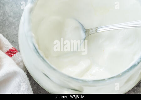 In casa lo yogurt di capra in recipiente di vetro con cucchiaio / probiotico di crema pasticcera. Prodotto organico. Foto Stock