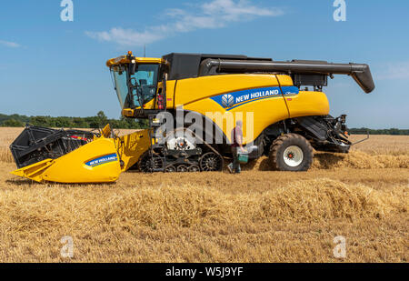 Cheltenham, Gloucestershire, Inghilterra, Regno Unito, mietitrebbia driver con toolbox controllando la sua macchina Foto Stock