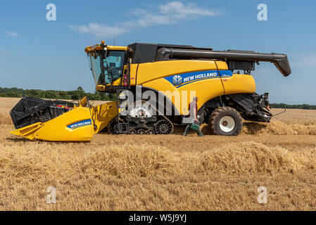 Cheltenham, Gloucestershire, Inghilterra, Regno Unito, mietitrebbia driver con toolbox controllando la sua macchina Foto Stock