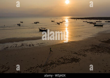 Antenna fuco vista delle tradizionali barche longtail al di ancoraggio durante un tramonto tropicale sull'oceano Foto Stock