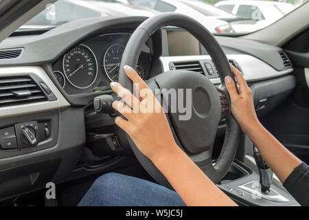 La ragazza con la manicure tiene le mani sul volante della vettura Foto Stock