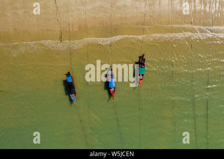 Top down vista aerea di colorati in legno tradizionali barche Longtail ormeggiato a una sabbiosa spiaggia tropicale Foto Stock