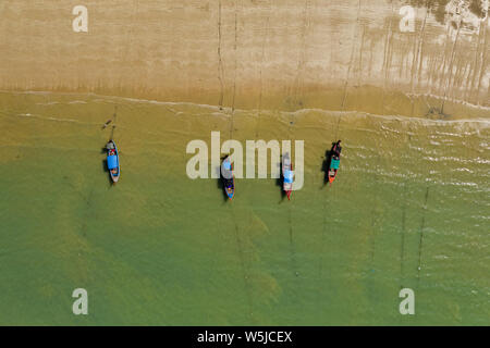 Top down vista aerea di colorati in legno tradizionali barche Longtail ormeggiato a una sabbiosa spiaggia tropicale Foto Stock