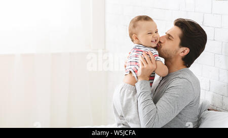 Giovane uomo baciando la sua adorabile figlio bambino, godendo di servizio baby Foto Stock