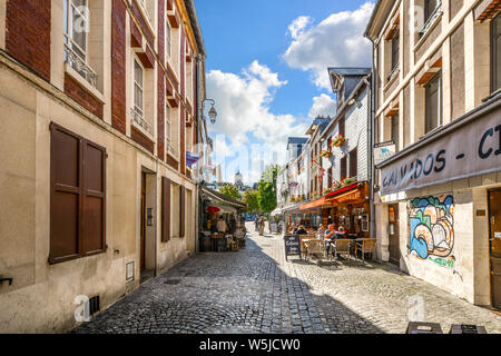 I turisti di pranzare in un cafè sul marciapiede in una pittoresca strada posteriore in Normandia villaggio di Honfleur, Francia. Foto Stock