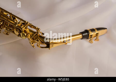 Beautiful golden sassofono sul delicato bianco sullo sfondo di seta Foto Stock