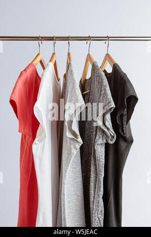 Capsula concetto guardaroba. T-shirt in tonalità di colori neutri e appeso su un rack di abbigliamento. Guardaroba minimalista. Foto Stock