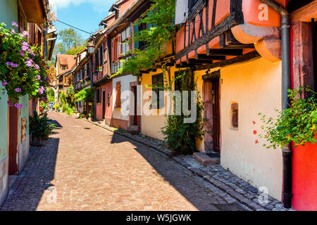 Colorato pittoresco viale nella città vecchia di Kaysersberg, Alsazia strada del vino, Francia, semi-case con travi di legno con decorazioni di fiori Foto Stock