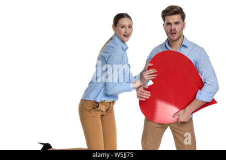 Giovane coppia felice a giocare con un grande cuore rosso su sfondo bianco Foto Stock