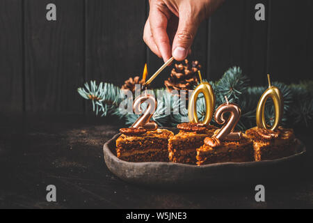 Nuovo anno 2020. Torta di festa con candele su uno sfondo scuro, copia dello spazio. Foto Stock