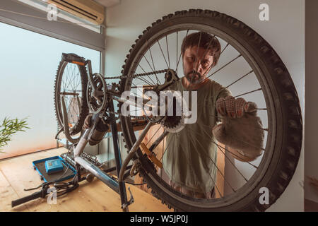 Uomo che ripara il vecchio hardtail mountain bike in officina, il fuoco selettivo Foto Stock