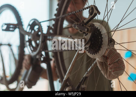 Uomo che ripara il vecchio hardtail mountain bike in officina, il fuoco selettivo Foto Stock