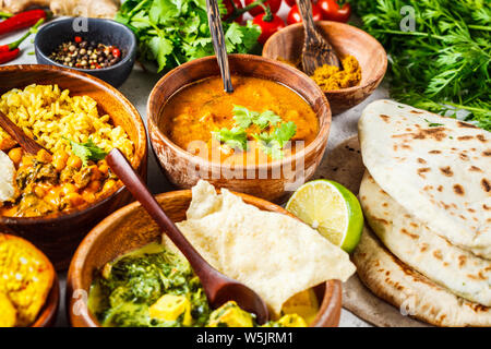 Il cibo tradizionale cucina Indiana. Dal, palak paneer, palline di formaggio, curry, riso, chapati, chutney in ciotole di legno su sfondo bianco. Foto Stock