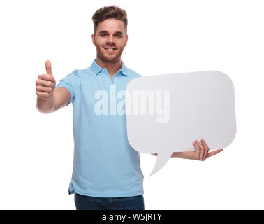 Attraente uomo informale stive vuote discorso bolla e fa segno ok mentre in piedi su sfondo bianco, ritratto foto Foto Stock
