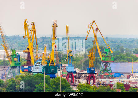 Paesaggio industriale con gru portuali di giallo e blu nel porto sullo sfondo della vista della citta'. Foto Stock