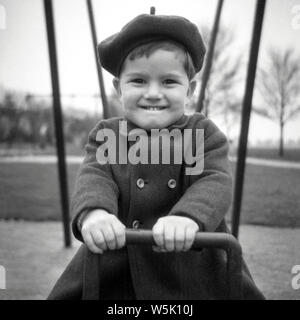 Un giovane ragazzo giocando sulle altalene a Northampton in 1952 Foto Stock