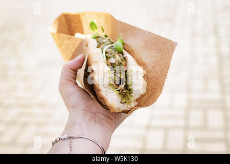 Vegana Vegetariana, hot dog con salsiccia di soia in mano femmina a un festival di strada Foto Stock